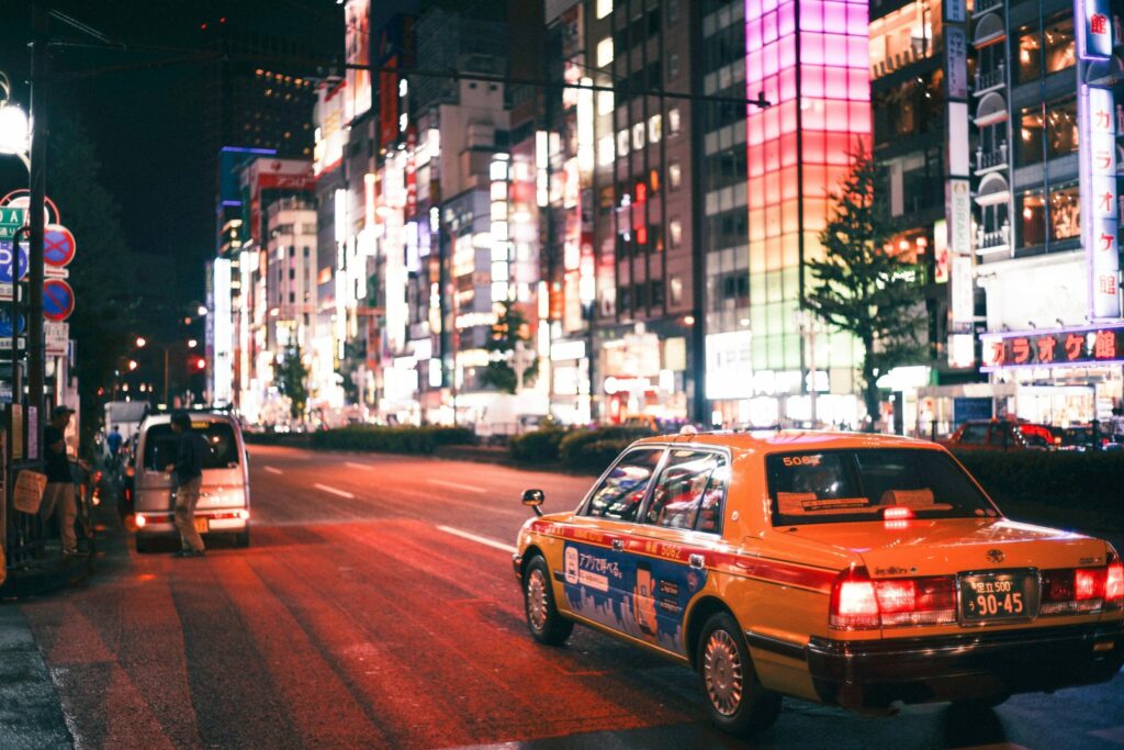 Taxi driving down a street with many lit up signs and billboards.