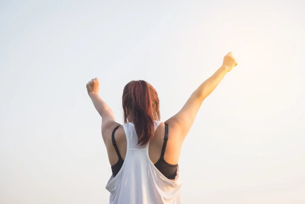 photo of woman with her arms up in celebration